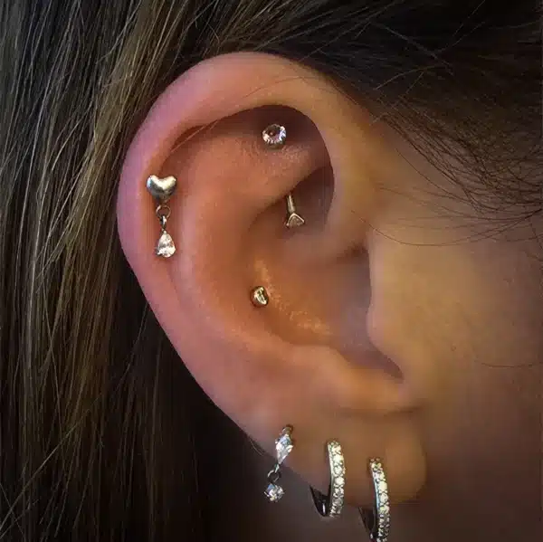 Customer Mel’s ear piercings featuring Lunar Heart Titanium Dangle, Silver Sparkle Titanium Diamond Labret, and Nova Titanium Banana Bar in helix, third lobe, and rook