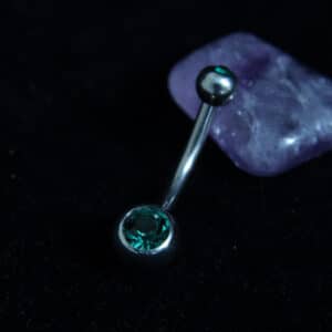 Silver titanium belly bar with emerald green Czech crystal jewel and 4mm and 6mm ball ends.