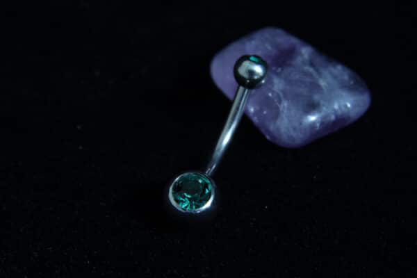Silver titanium belly bar with emerald green Czech crystal jewel and 4mm and 6mm ball ends.