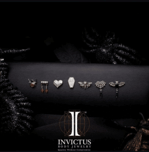 Promotional image showcasing the Invictus 14kt Gold Threadless Dripping Fangs Top with Garnet Marquise Gem Dangle. Crafted from solid nickel-free gold with a durable threadless post, this gothic-inspired piece features a blood-red garnet dangle, offering a bold yet elegant statement for ear jewelry enthusiasts.
