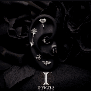 Promotional image showcasing the Invictus 14kt Gold Threadless Dripping Fangs Top with Garnet Marquise Gem Dangle. Crafted from solid nickel-free gold with a durable threadless post, this gothic-inspired piece features a blood-red garnet dangle, offering a bold yet elegant statement for ear jewelry enthusiasts.